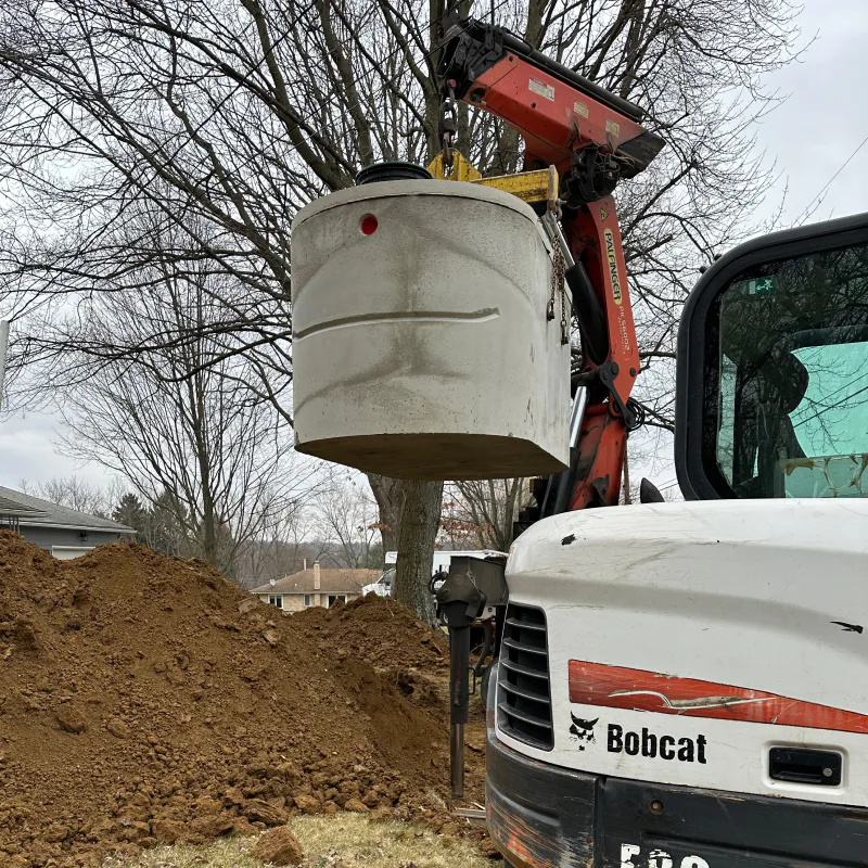 cylindrical septic tank being lowered into ground