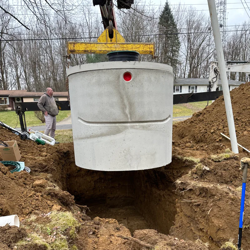 light gray septic tank being lowered into ground